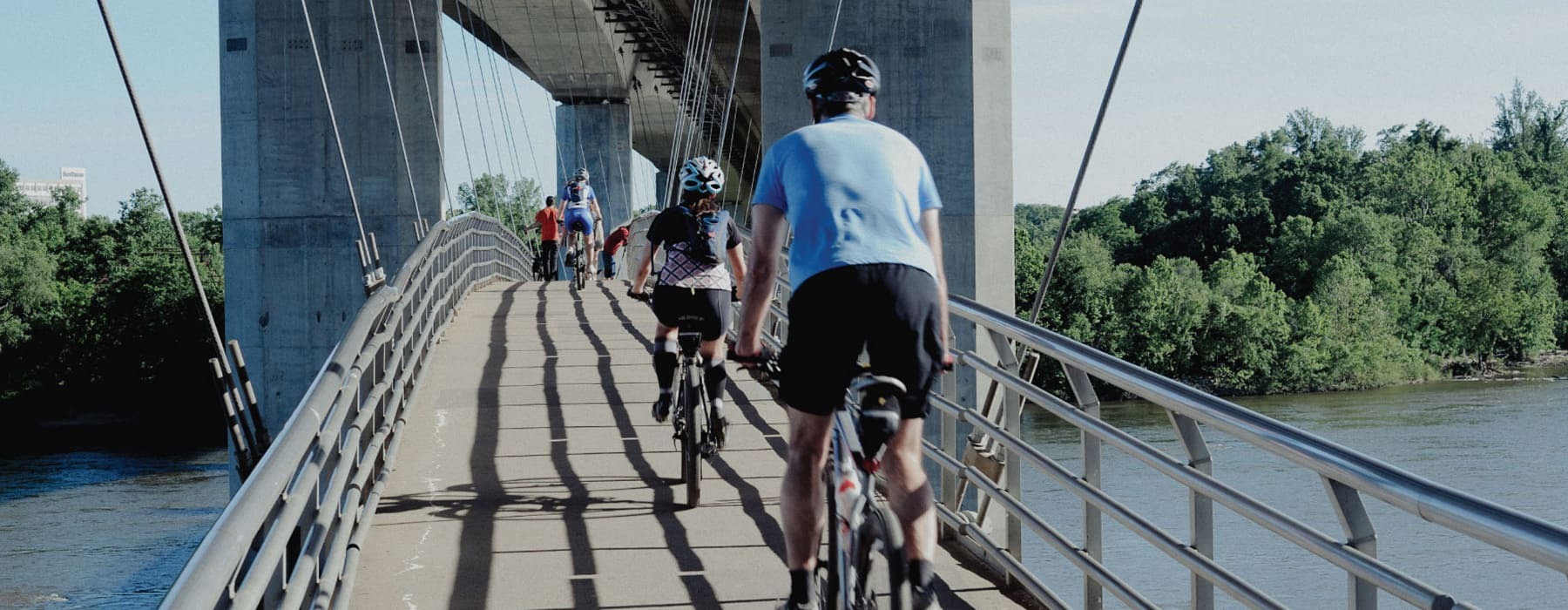 lifestyle image of people riding across a bridge on their bicycles